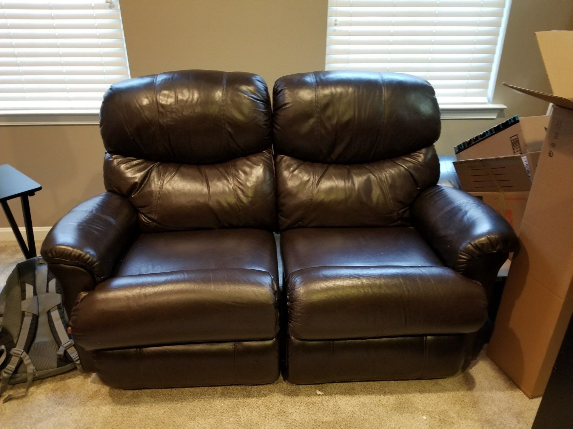 Brown leather double recliner in front of a window.