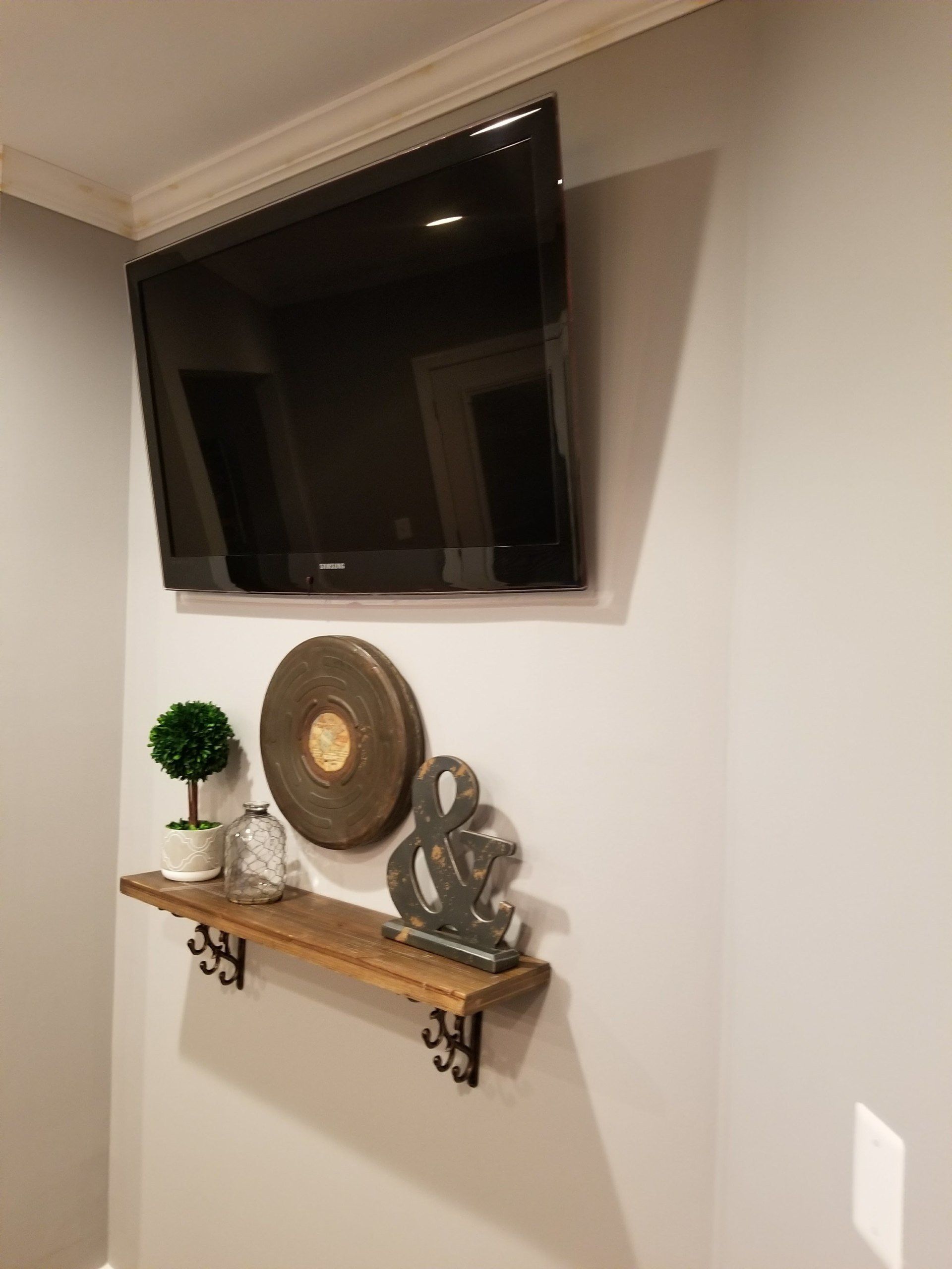 wall mounted television with tree, jar, and gong on a shelf by furniture assembly team