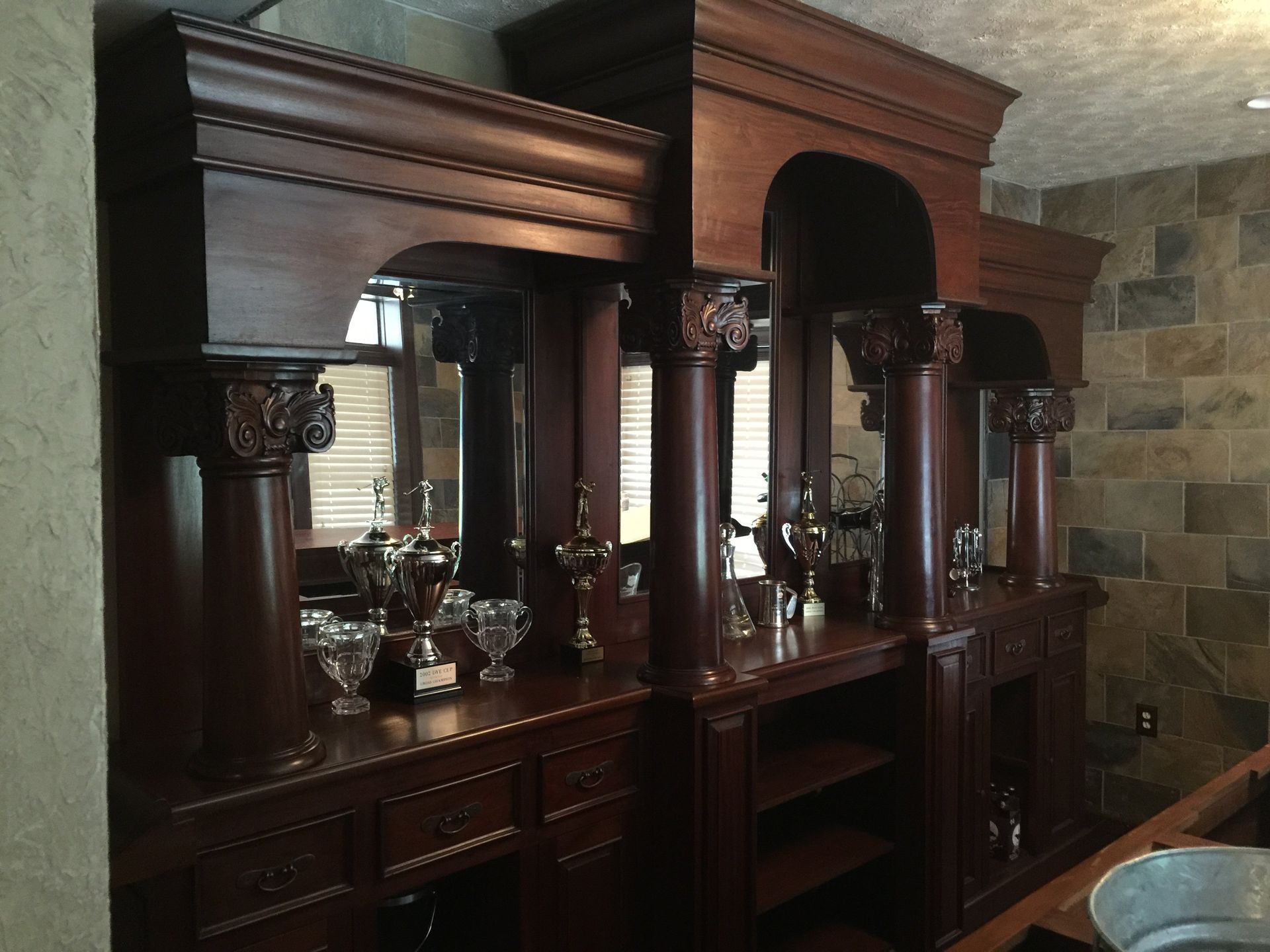 Dark wood bar with columns, mirrored back, and glassware on display.