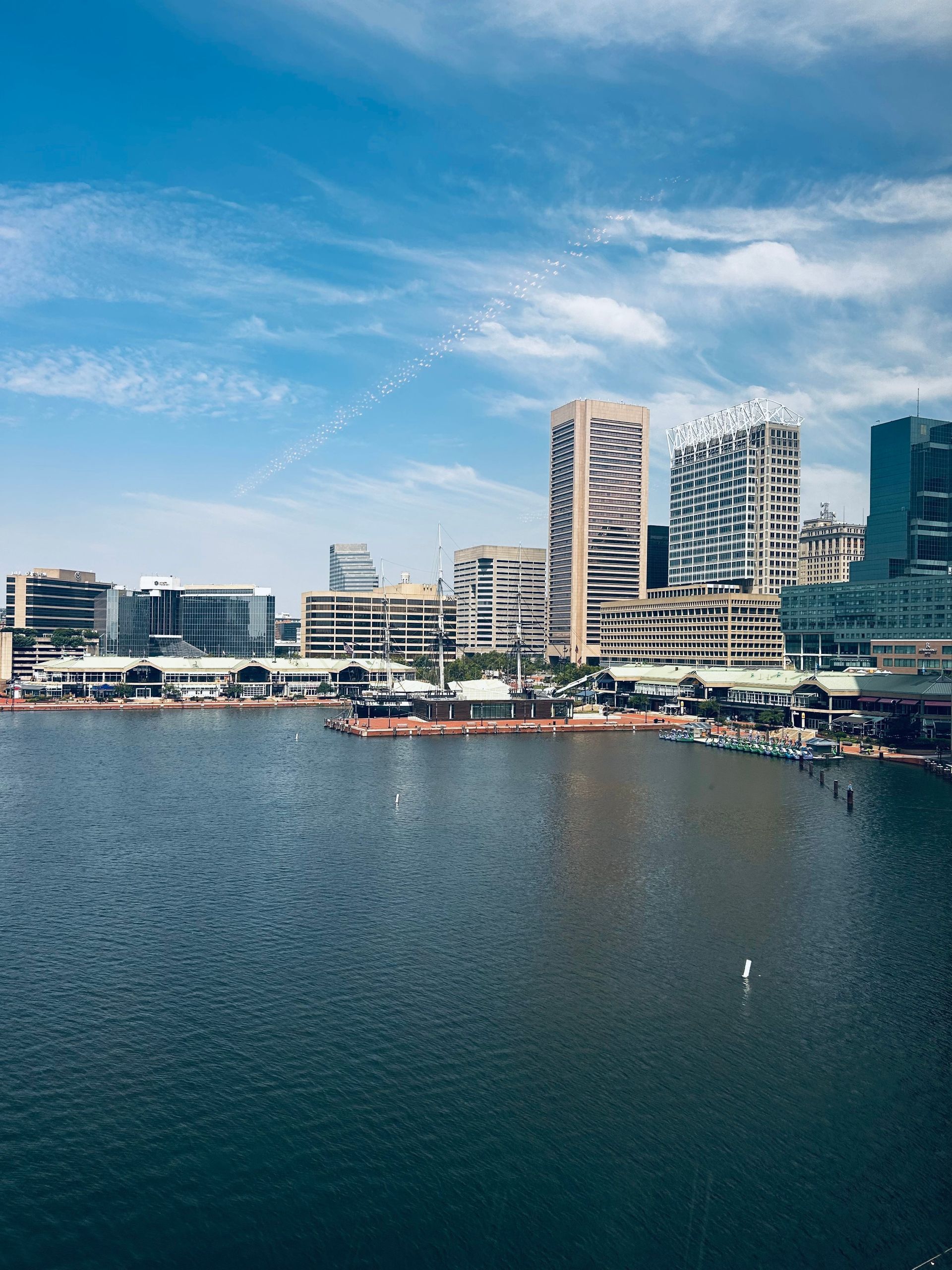 Harbor waterfront with boats, high-rise buildings, and blue sky over calm water