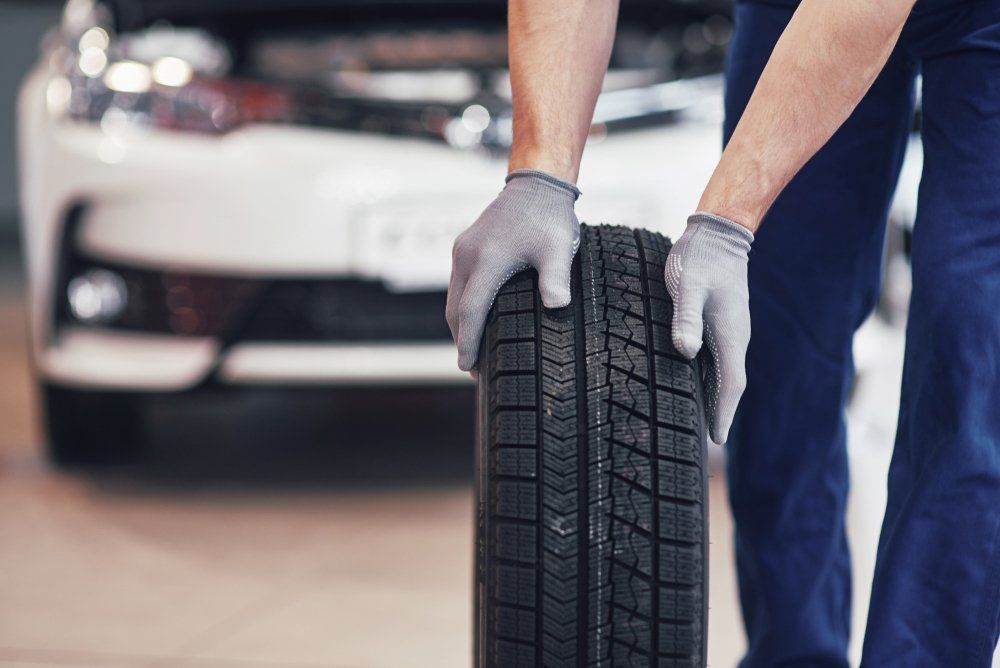 Mechanic Holding a Tire Tire at the Repair Garage — Affordable Tyre Repairs in Gladstone, QLD