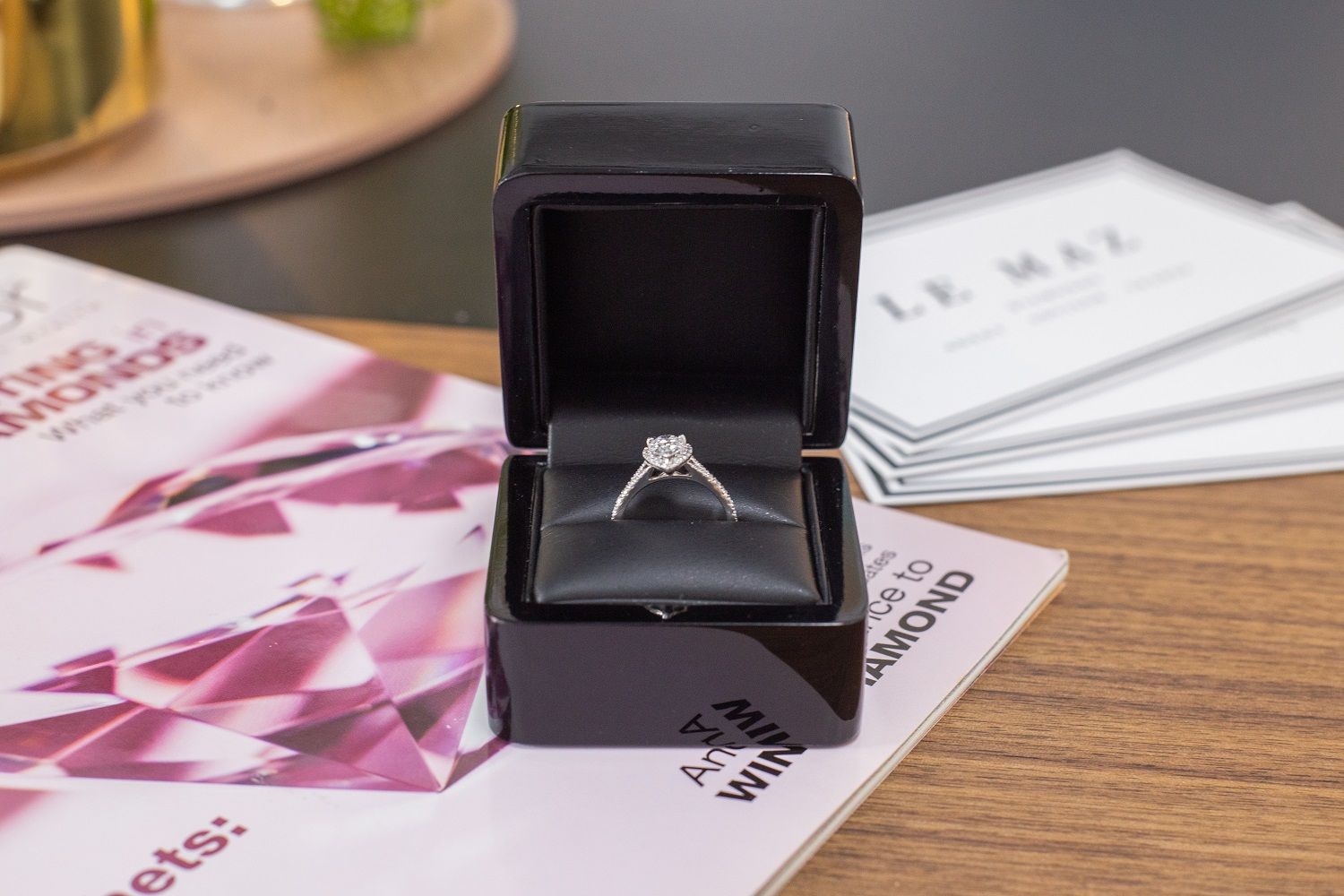 A diamond ring is in a black box on a table.