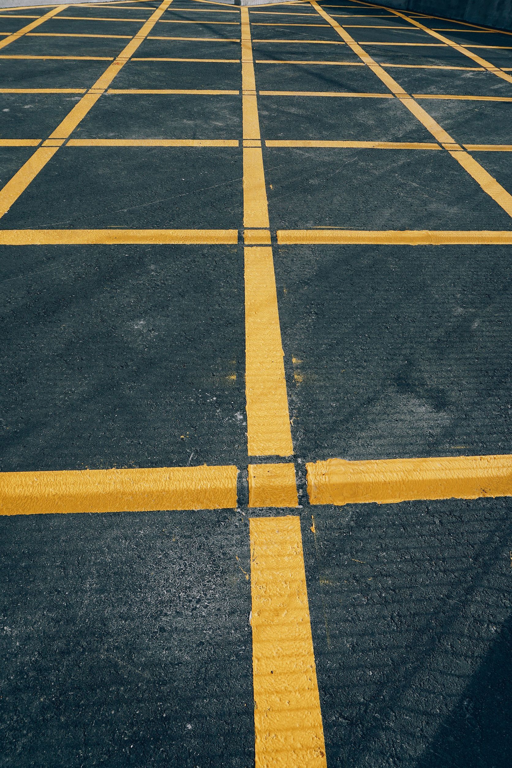 A close up of a parking lot with yellow lines on it.