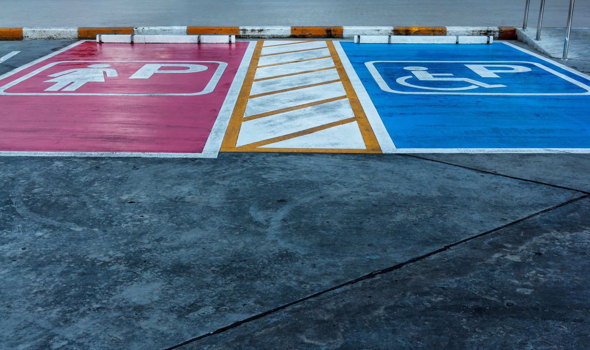 A parking lot with a handicapped parking spot and a red and blue handicapped parking spot.
