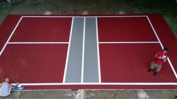 A man in a red shirt is standing on a red tennis court