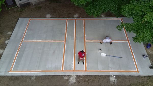 An aerial view of a tennis court being built in a backyard.