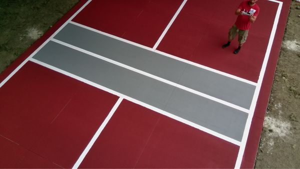 A man in a red shirt is standing on a red tennis court.