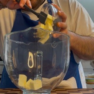 Un uomo sta aggiungendo il burro in una ciotola di vetro con una spatola