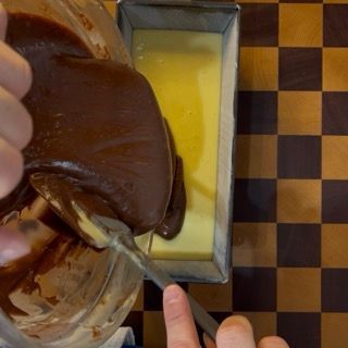 Primo piano degli impasti (bianco e cacao) stratificati nello stampo prima della cottura.