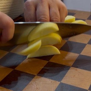 Taglio delle mele sbucciate a fettine regolari.