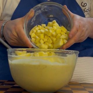 Mescolamento delle mele nell'impasto per una distribuzione uniforme nel dolce da colazione.