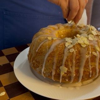Preparazione e distribuzione della glassa di zucchero a velo e limone sulla torta.