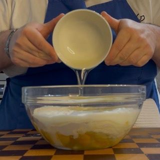 Versamento dei liquidi (latte, olio) sopra la farina e lo zucchero per la base universale.