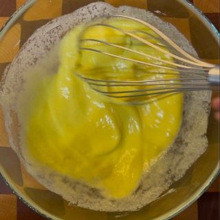 Una persona sta mescolando un liquido giallo in una ciotola.