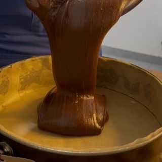 Una persona sta versando del cioccolato in una tortiera.