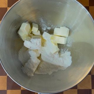 Una ciotola di metallo piena di burro e zucchero a velo