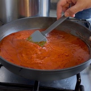 Una persona sta mescolando una padella di salsa con una spatola