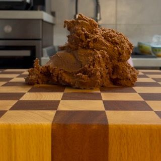 Un pezzo di pasta al cioccolato è appoggiato su un tagliere di legno