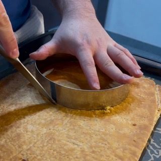 Una persona sta usando un anello di metallo per tagliare un pezzo di pane