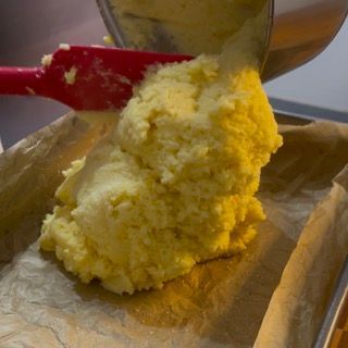 Una persona versa la pastella in una padella con una spatola