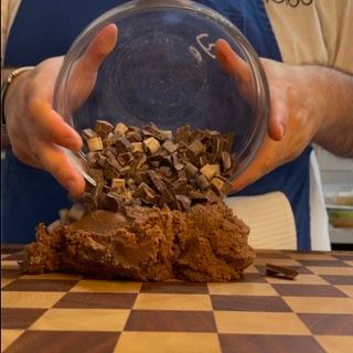 Una persona sta versando gocce di cioccolato in una ciotola di vetro