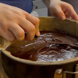 Una persona sta mescolando una pentola di salsa al cioccolato con una spatola