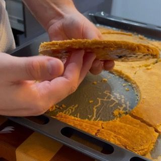 Una persona tiene un pezzo di cibo sopra una pentola di cibo