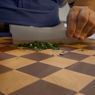 Una persona sta tagliando i cipollotti su un tagliere a scacchi