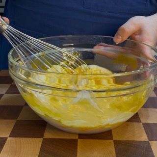 Una persona sta sbattendo le uova in una ciotola di vetro