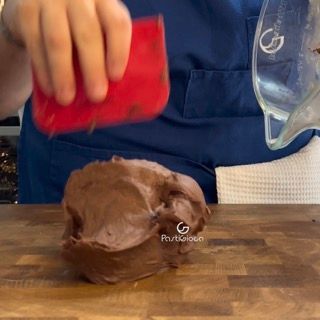 Una persona tiene una spatola rossa sopra un pezzo di cioccolato