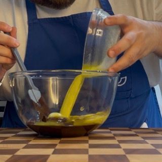 Un uomo con un grembiule sta versando del liquido in una ciotola