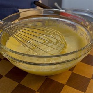 Una ciotola di liquido giallo con una frusta dentro