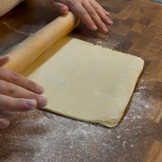 Una persona sta stendendo un pezzo di pasta con un mattarello