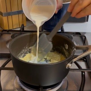 Una persona che versa il latte in una pentola con un cucchiaio