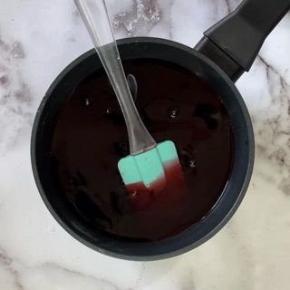 Una pentola piena di liquido rosso con una spatola dentro.