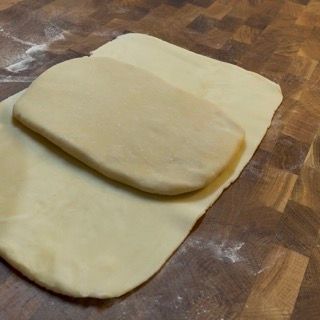 Due pezzi di pasta sono adagiati su una superficie di legno