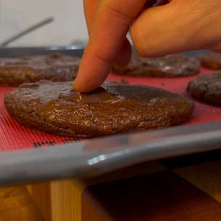 Un primo piano del dito di una persona su un biscotto su un vassoio