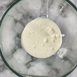 Una ciotola di vetro piena di un liquido bianco su un tavolo.