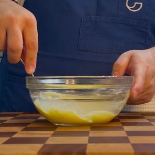 Una persona sta mescolando un liquido giallo in una ciotola di vetro