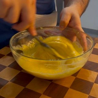 Una persona sta mescolando un liquido giallo in una ciotola di vetro