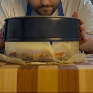 Un uomo tiene in mano una tortiera su un tagliere