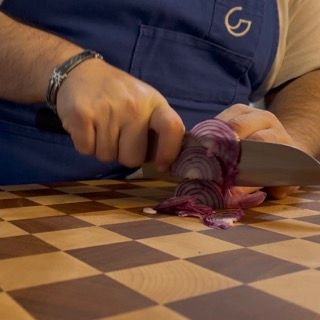 Un uomo sta tagliando una cipolla su un tagliere a scacchi