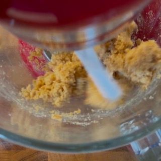 Una persona sta mescolando un impasto in una ciotola di vetro con una spatola.