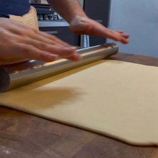 Una persona sta stendendo la pasta con un mattarello