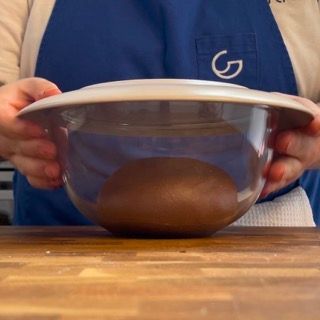 Una persona con un grembiule tiene in mano una ciotola di cibo