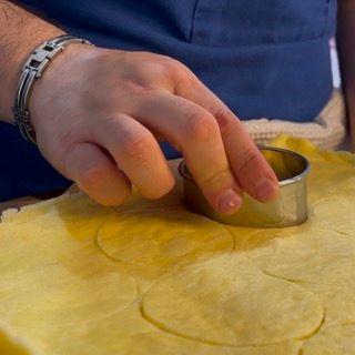 Una persona sta tagliando un ananas con un taglierino di metallo