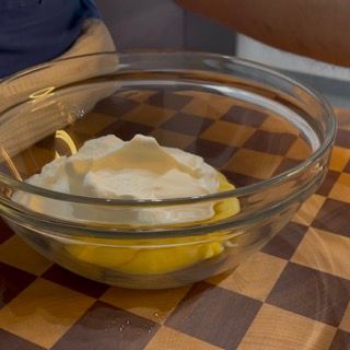 Una ciotola di vetro piena di un liquido giallo si trova su un tavolo a scacchi.