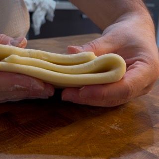 Una persona tiene in mano un pezzo di pasta.