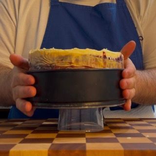 Un uomo con un grembiule tiene una torta tra le mani