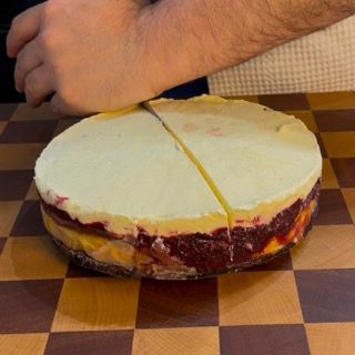 Una persona sta tagliando una cheesecake su una tavola a scacchi
